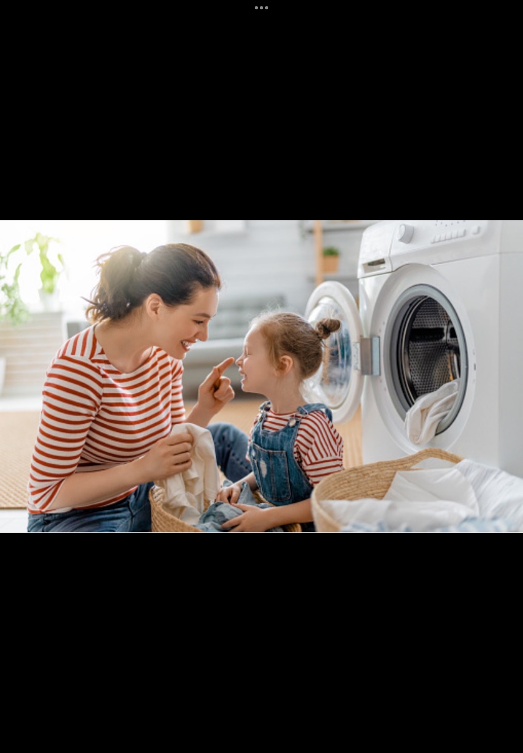 Mother and child doing laundry beside a washing machine